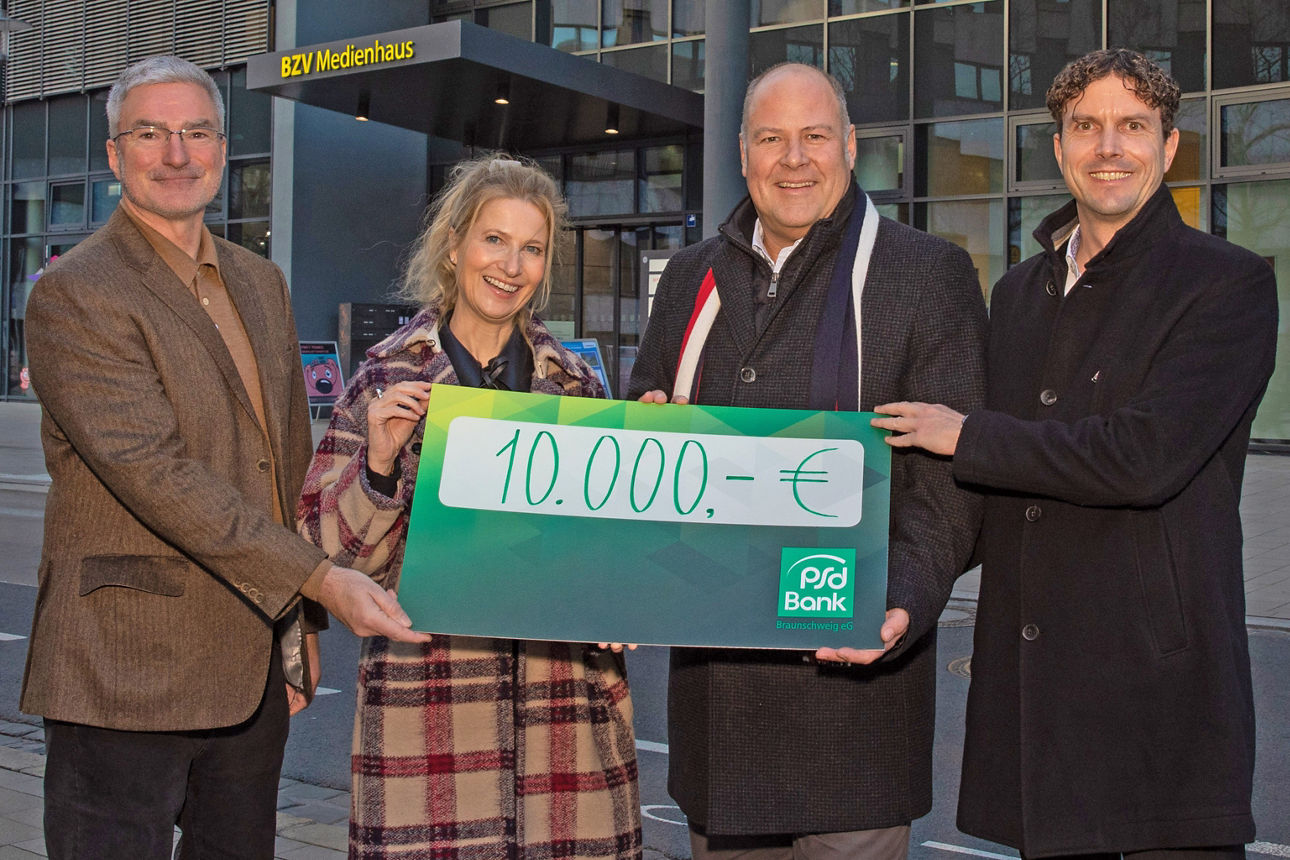 Vier Menschen halten einen Scheck