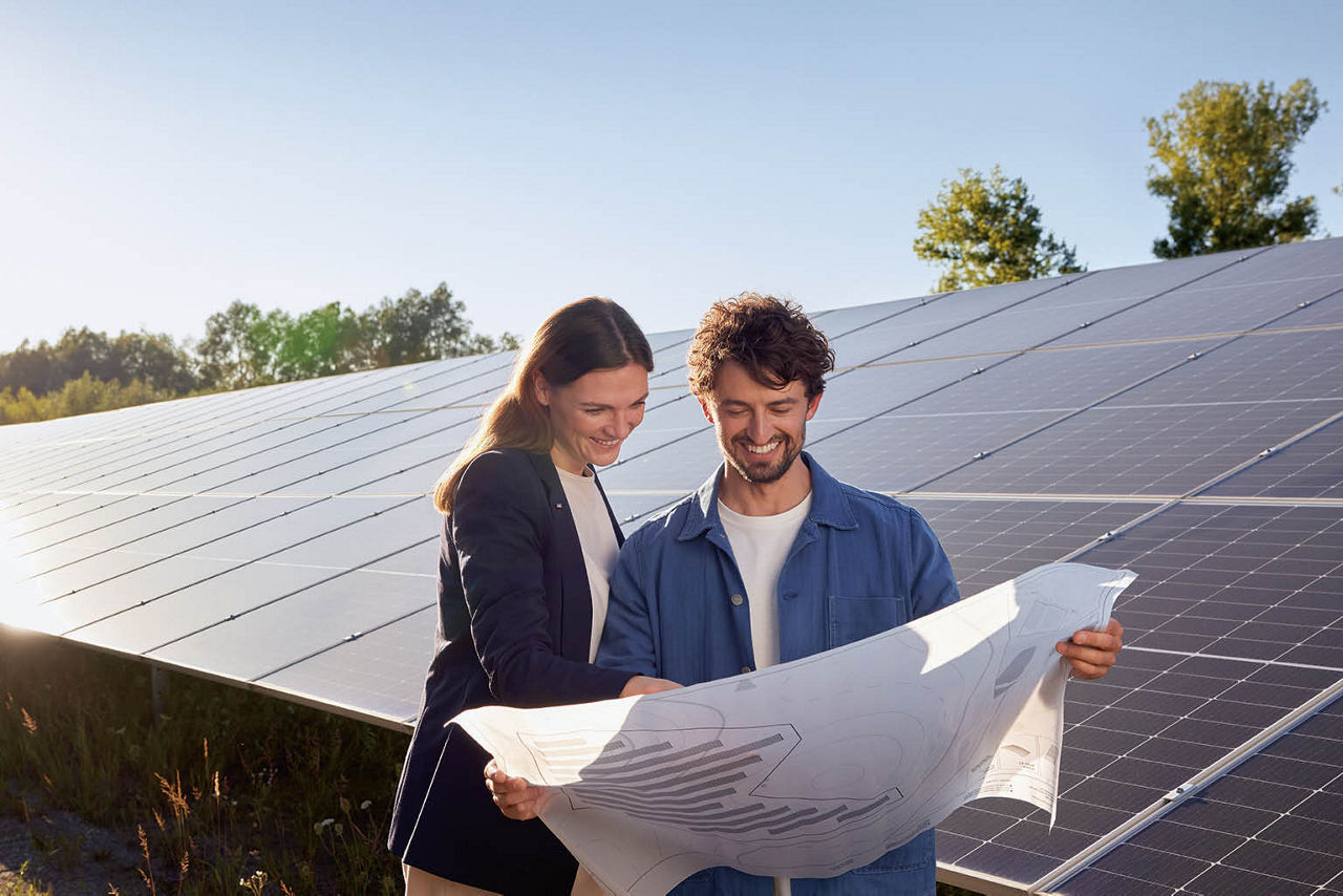 Mann und Frau mit Plan vor Solarpark