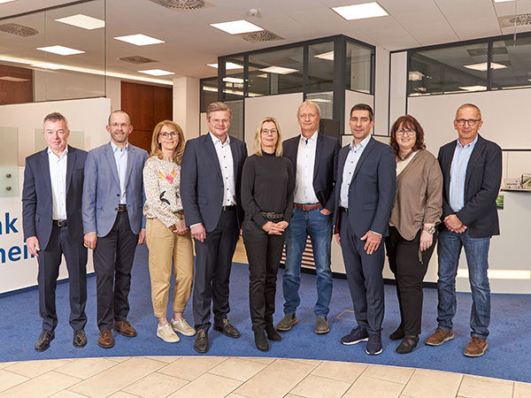 Eine Gruppe von acht Personen steht in einer Reihe vor einer Wand