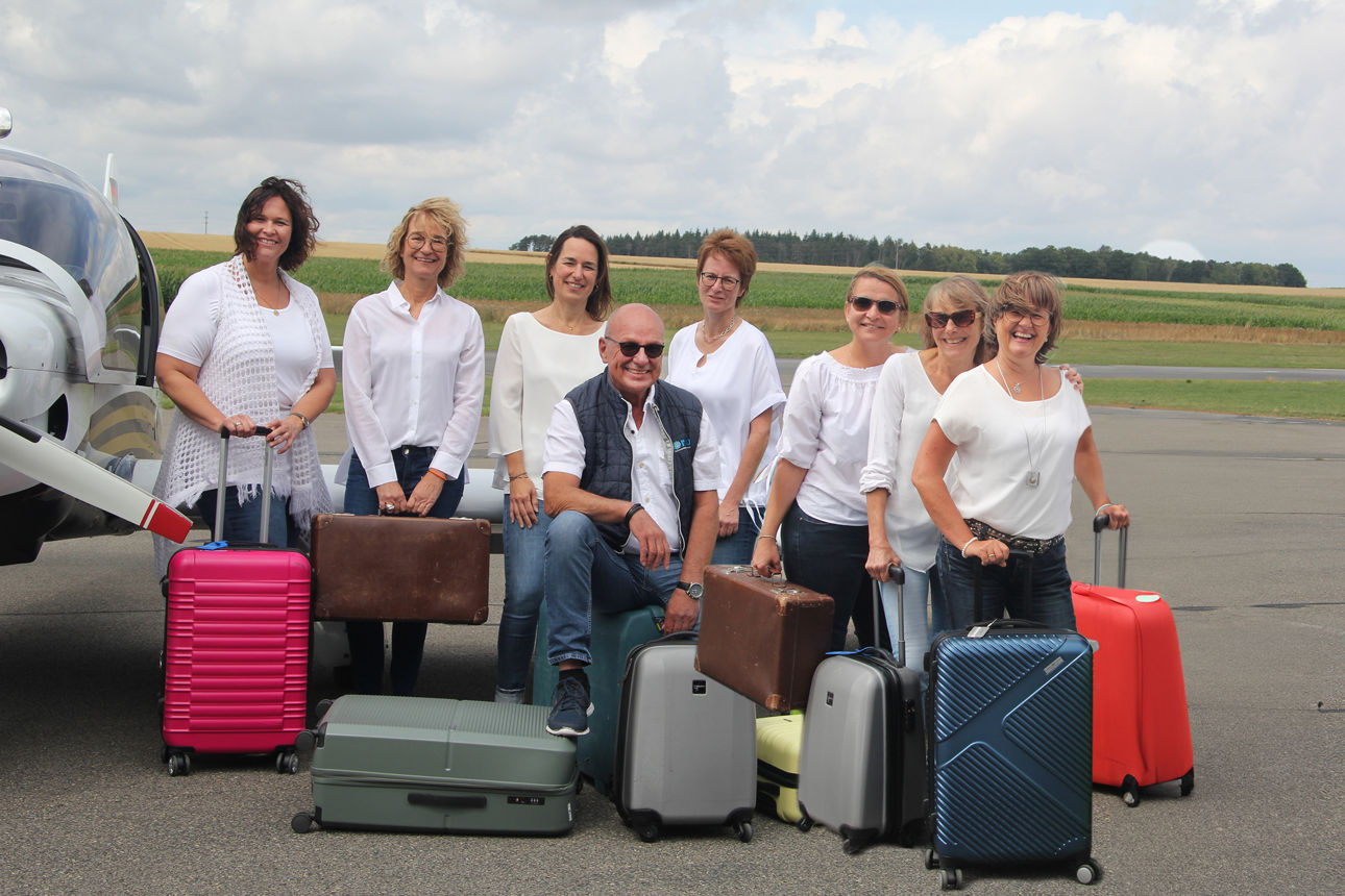 Das Team vom Reisecenter Odenwald mit Koffern auf einer Landebahn.