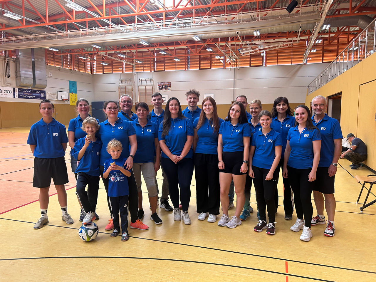 Ein Gruppenfoto von Kinder, Frauen und Männer in einer Sporthalle
