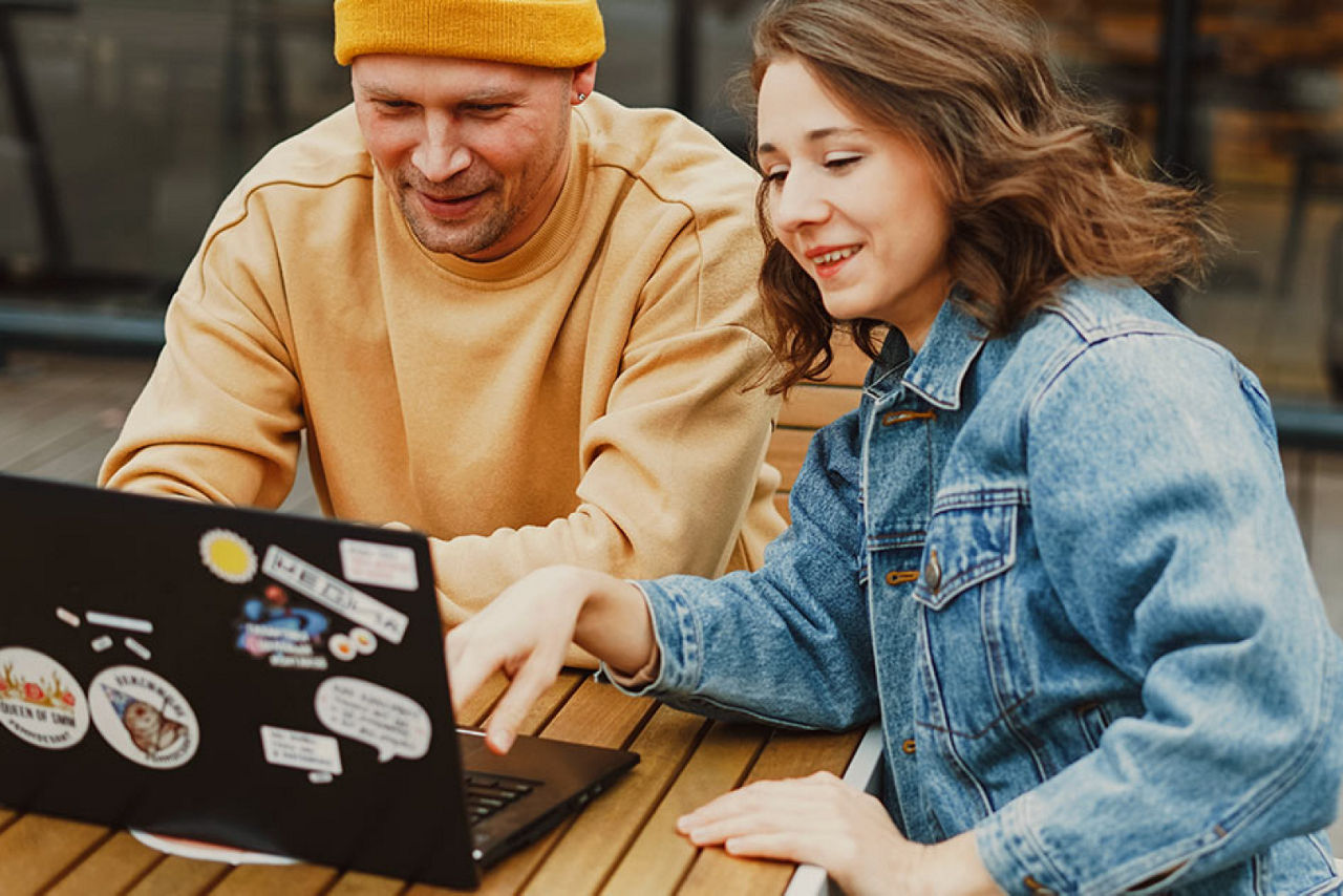 Junger Mann und junge Frau sitzen vor einem Laptop