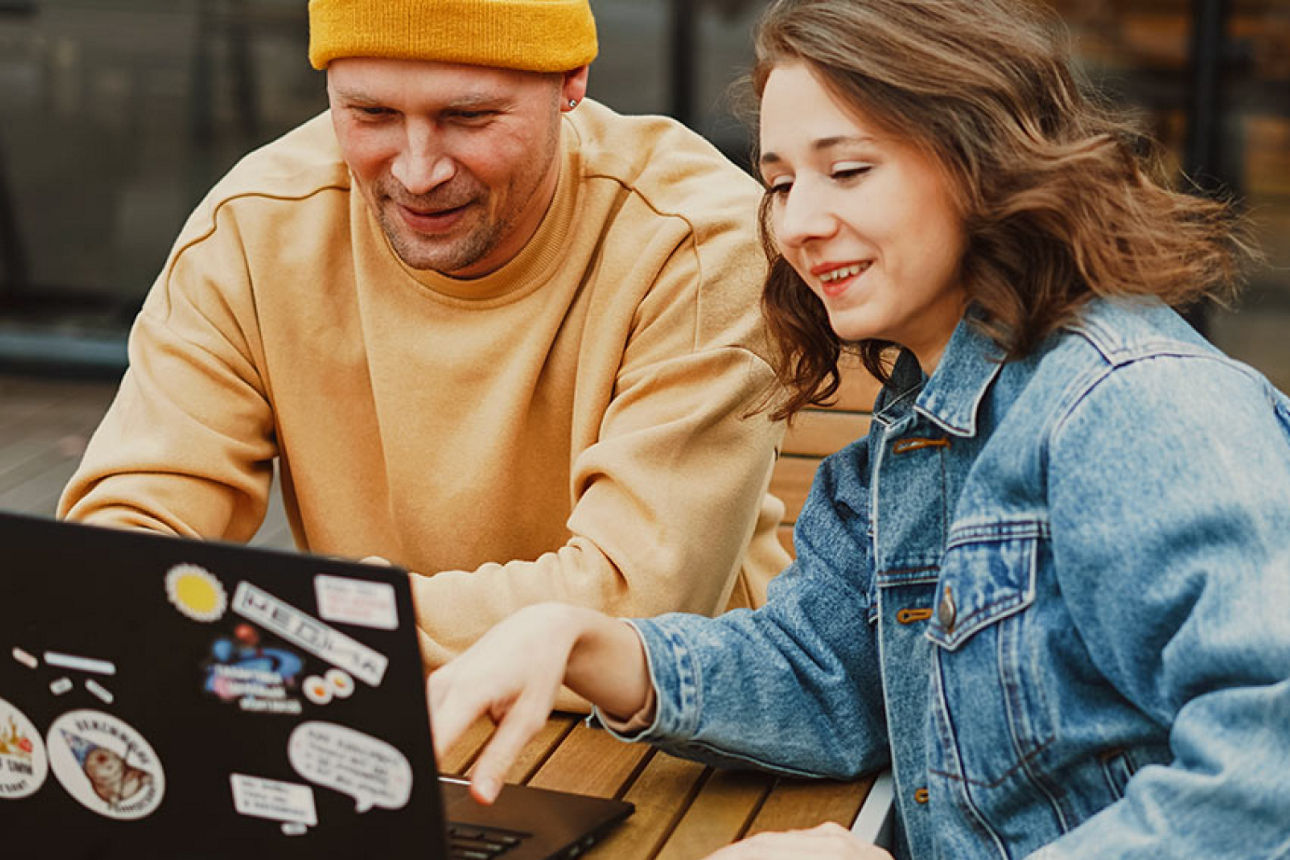 Junger Mann und junge Frau sitzen vor einem Laptop