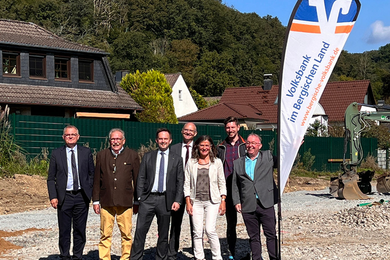 Personen stehen auf Baustelle vor Volksbank-Beachflag