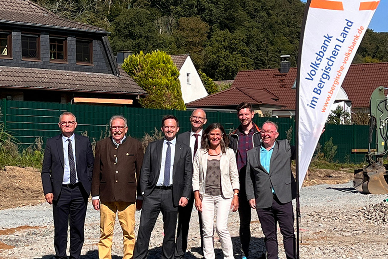 Personen stehen auf Baustelle vor Volksbank-Beachflag