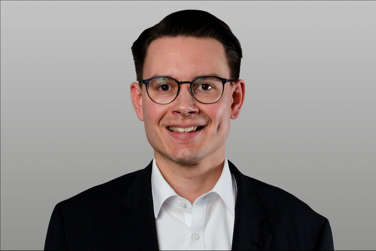 Baufinanzierungsspezialist Benjamin Schulz vor grauen Hintergrund
