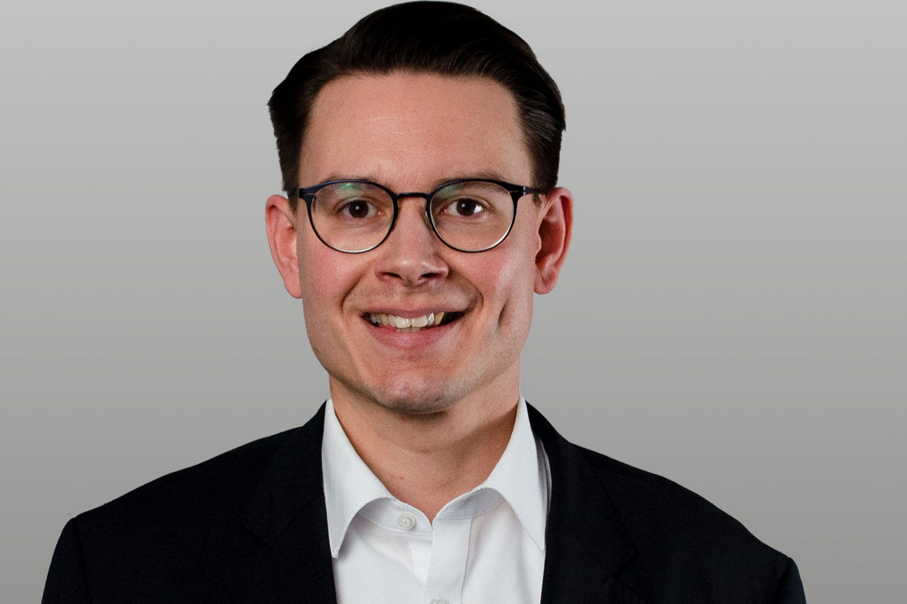 Baufinanzierungsspezialist Benjamin Schulz vor grauen Hintergrund