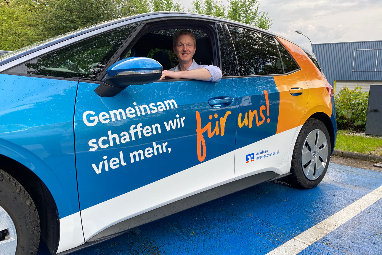 Kollege sitzt im Volksbank-Auto auf Parkplatz