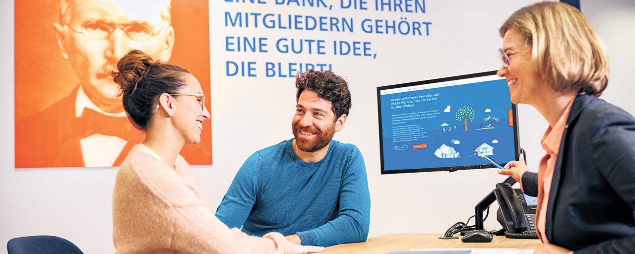 Lächelndes Ehepaar im Beratungsgespräch mit ihrer Bankberaterin.