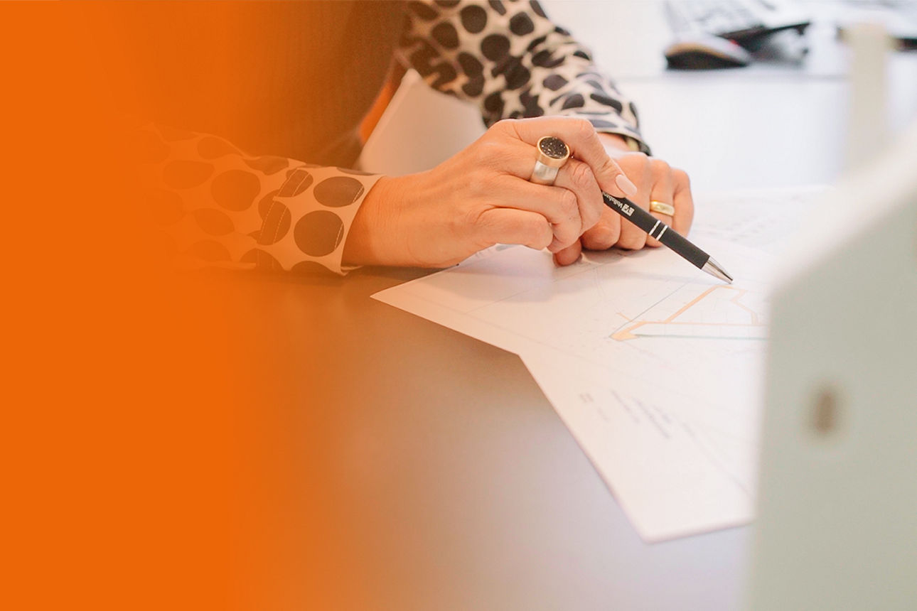 Ein Oranger Banner der nach rechts als Verlauf in einem Bild mündet, wo Dokumente unterzeichnet werden