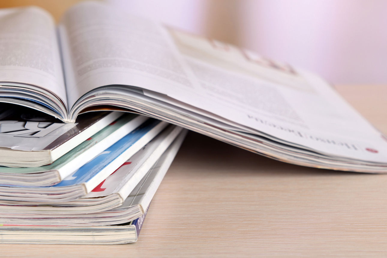 Zeitschriften gestappelt auf einem Holztisch.