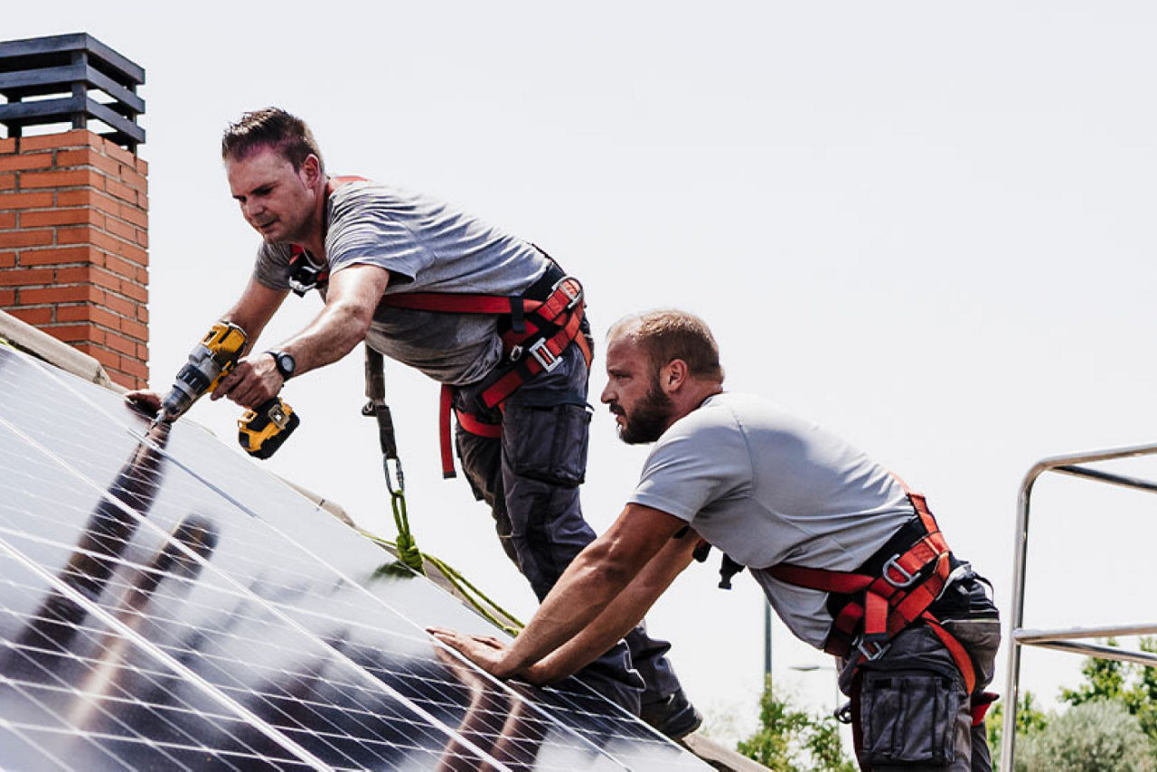 Zwei Männer installieren Solarzellen auf einem Dach