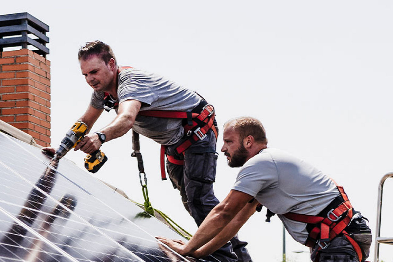 Zwei Männer installieren Solarzellen auf einem Dach