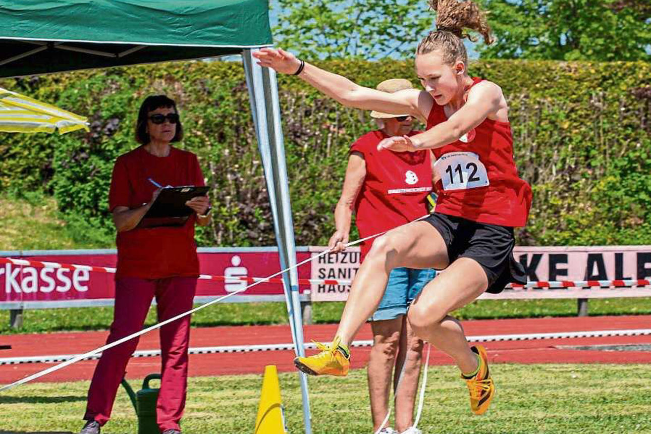 Weitsprung: Eine junge Frau spingt in ein Sandbecken.