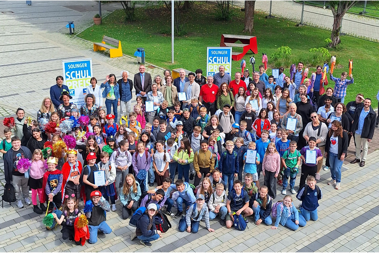 Schüler stehen jubelnd auf dem Schulhof