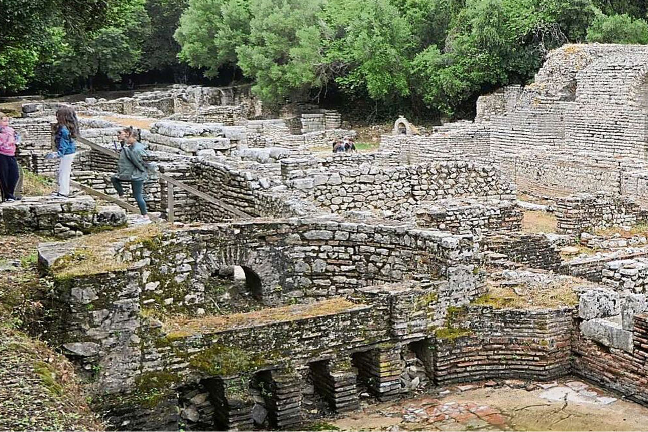 Die Ruinenstadt Butrint umgeben von grünen Bäumen.