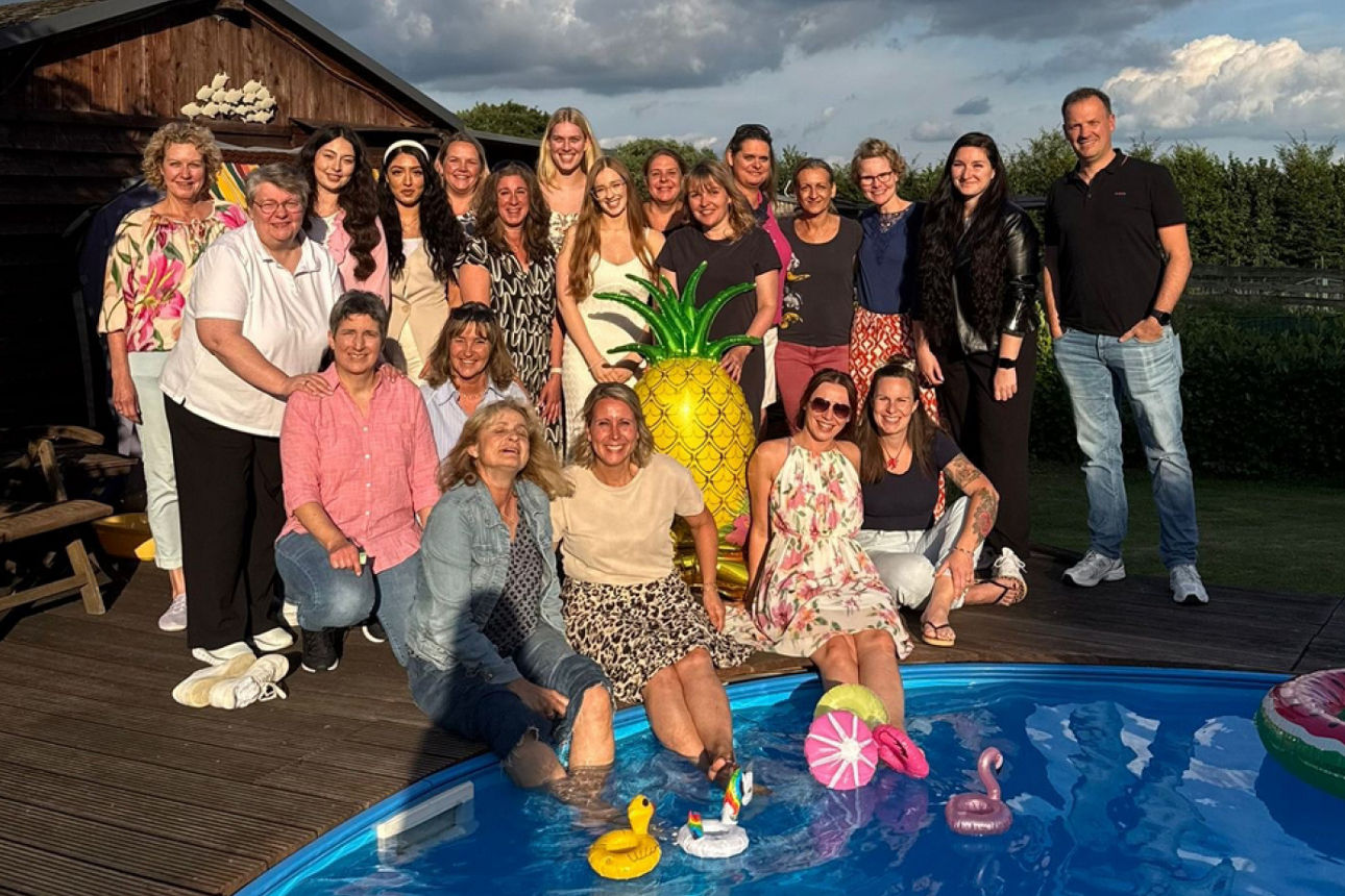 Kollegen stehen als Gruppe vor Pool im Garten