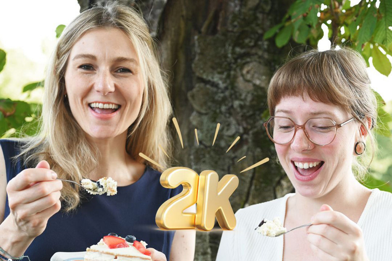 Zwei Kolleginnen strahlen und essen Kuchen 