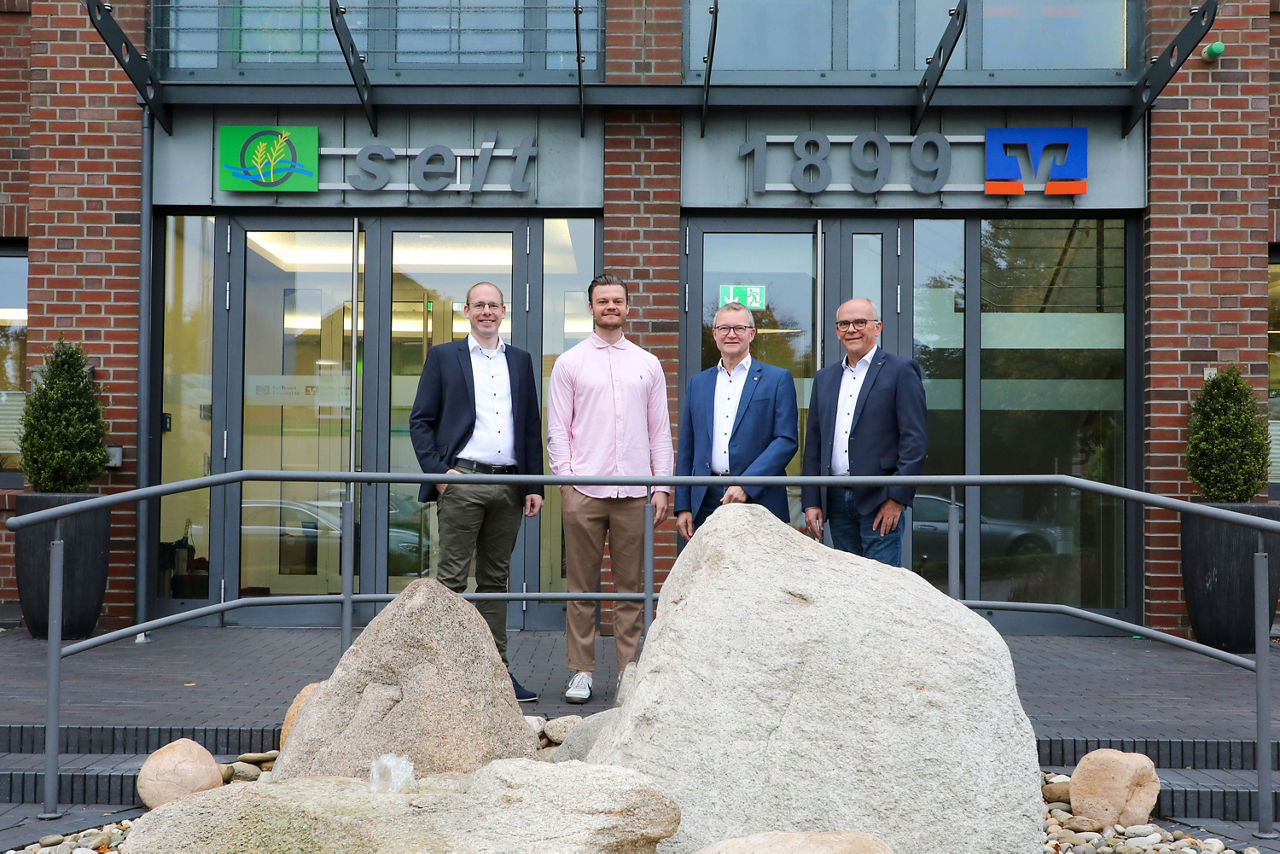 Vier Männder stehen vor dem Eingang der Raiffeisenbank Ems-Vechte eG