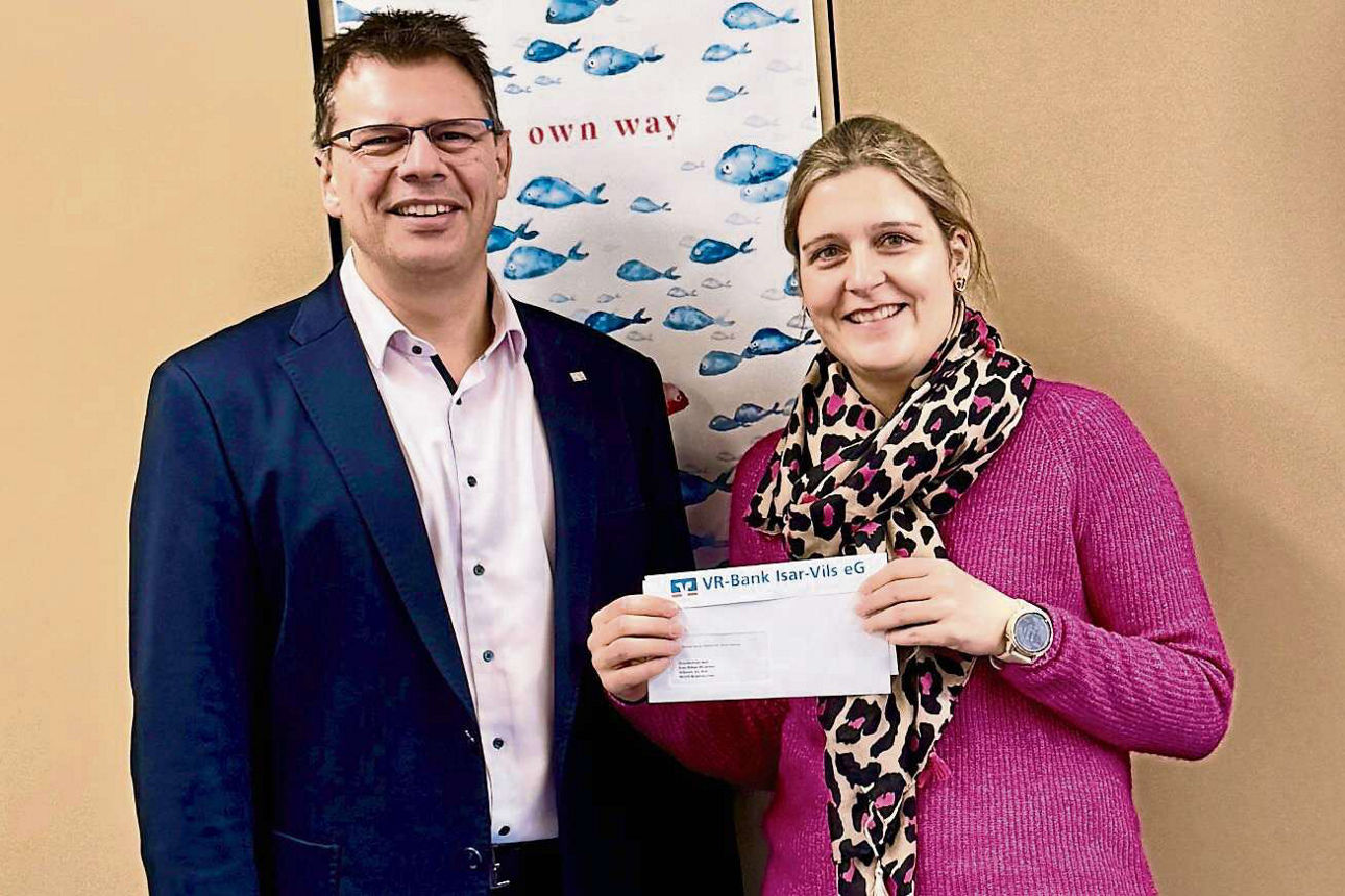 Ein freundlich lächelnder Mann im Anzug und eine freundlich lächelnde Frau halten einen Spendenbrief in die Kamera