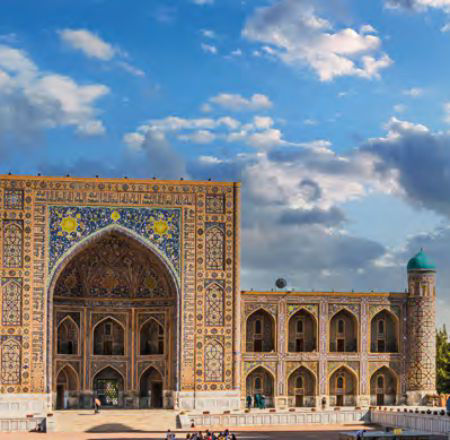 Das Bild zeigt ein schönes Gebäude, welches in Usbekistan steht. Im Hintergrund ist blauer Himmer mit Wolken. 