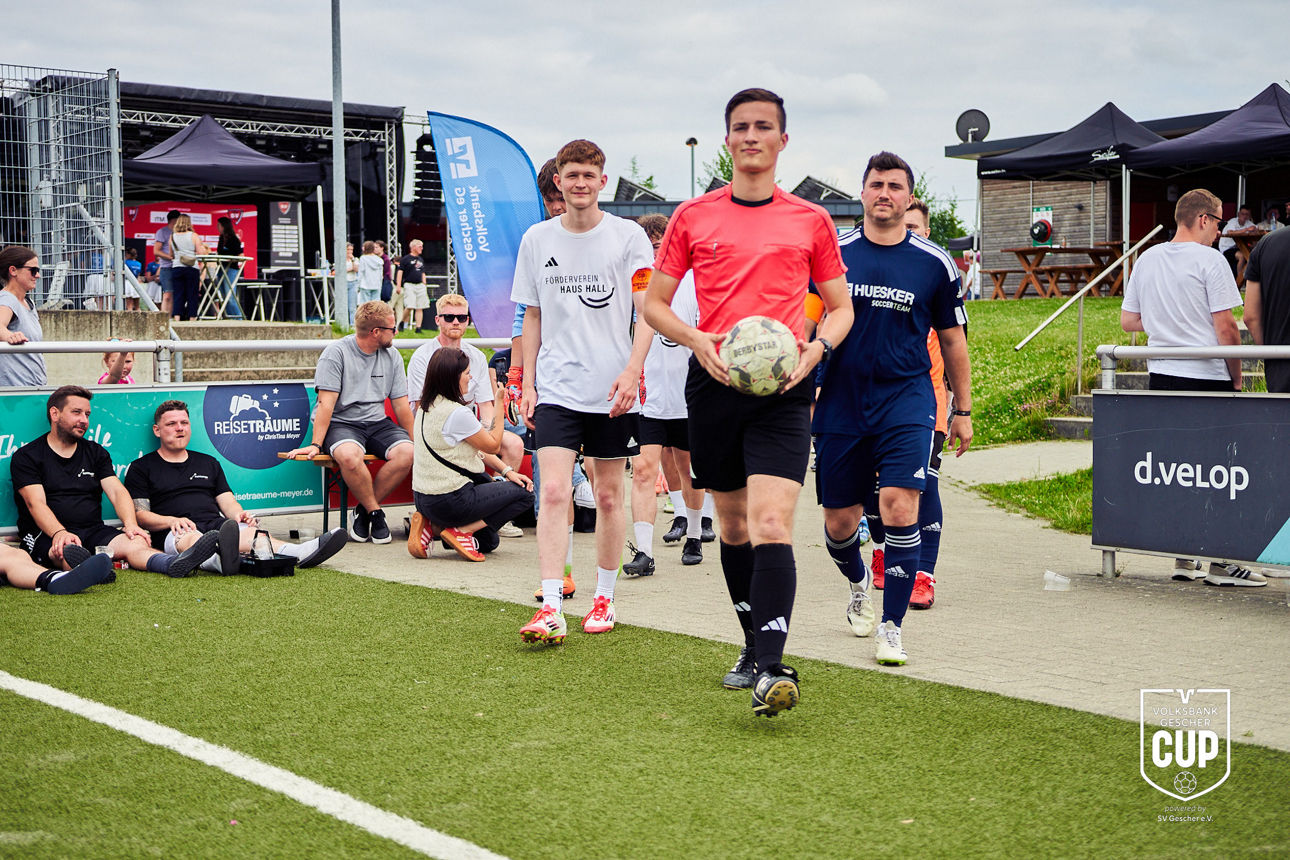 Ein Schiedsrichter läuft mit beiden Mannschaften auf das Spielfeld