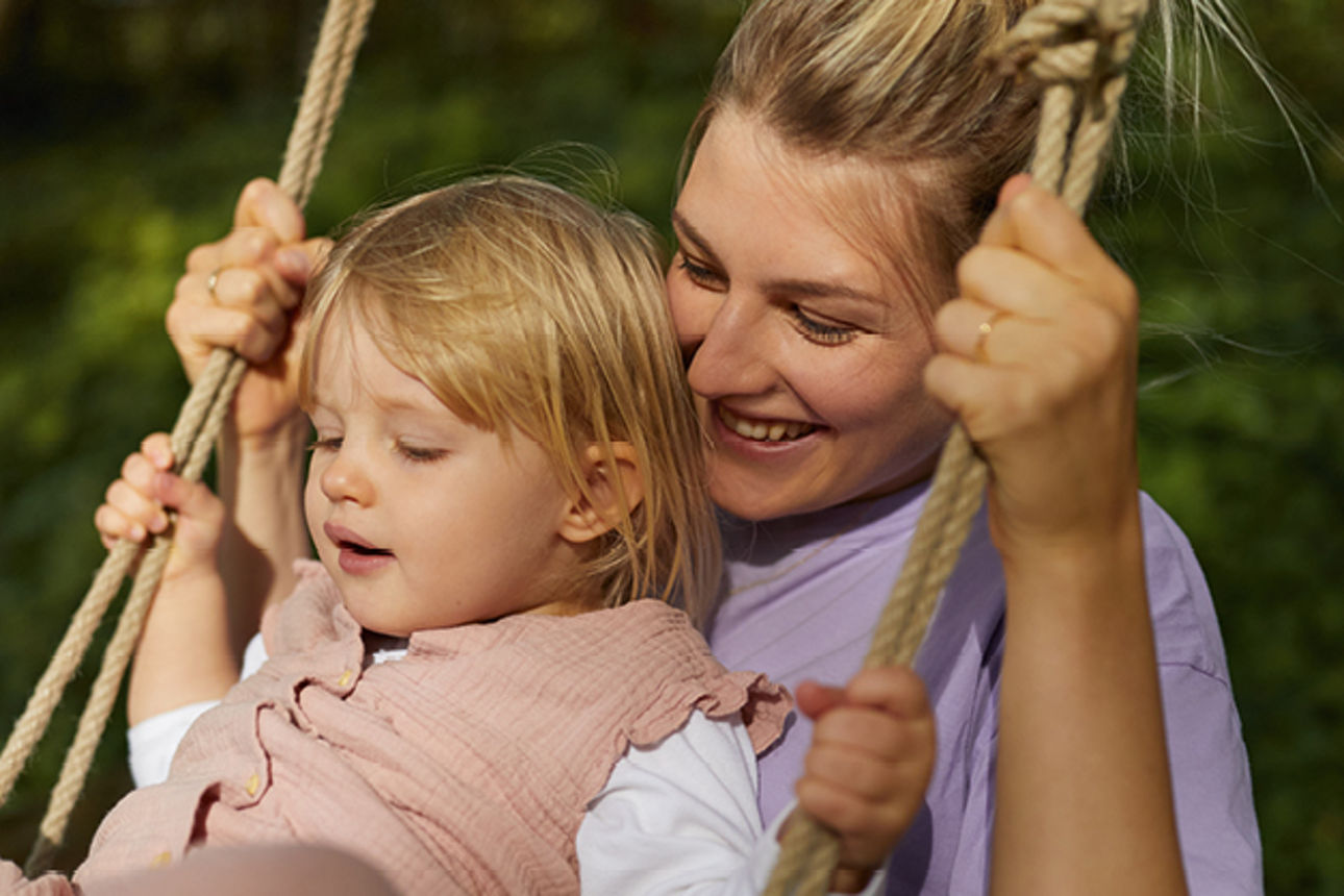 Mutter und Kind sitzen auf einer Schaukel