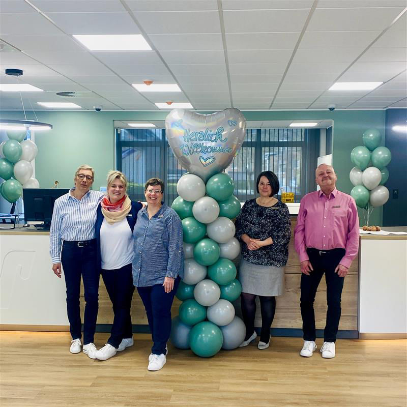 Fünf Mitarbeiter der Filiale Büderich posieren neben einer Ballonwand bei der Fertigstellung des Servicebereichs