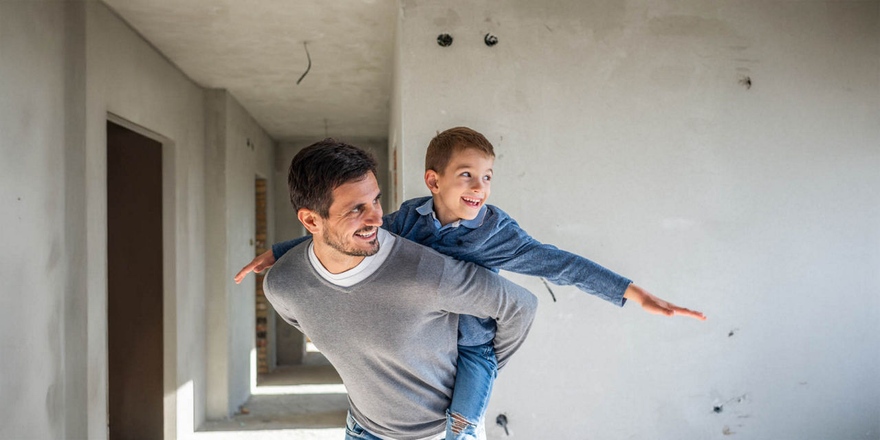 Vater und Sohn spielen  auf der Baustelle ihres Eigenheims