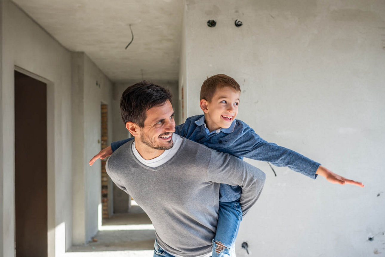Vater und Sohn spielen  auf der Baustelle ihres Eigenheims