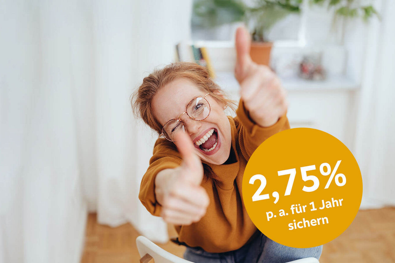 Junge Frau mit Brille zeigt zwei Daumen hoch und freut sich über das Festgeld