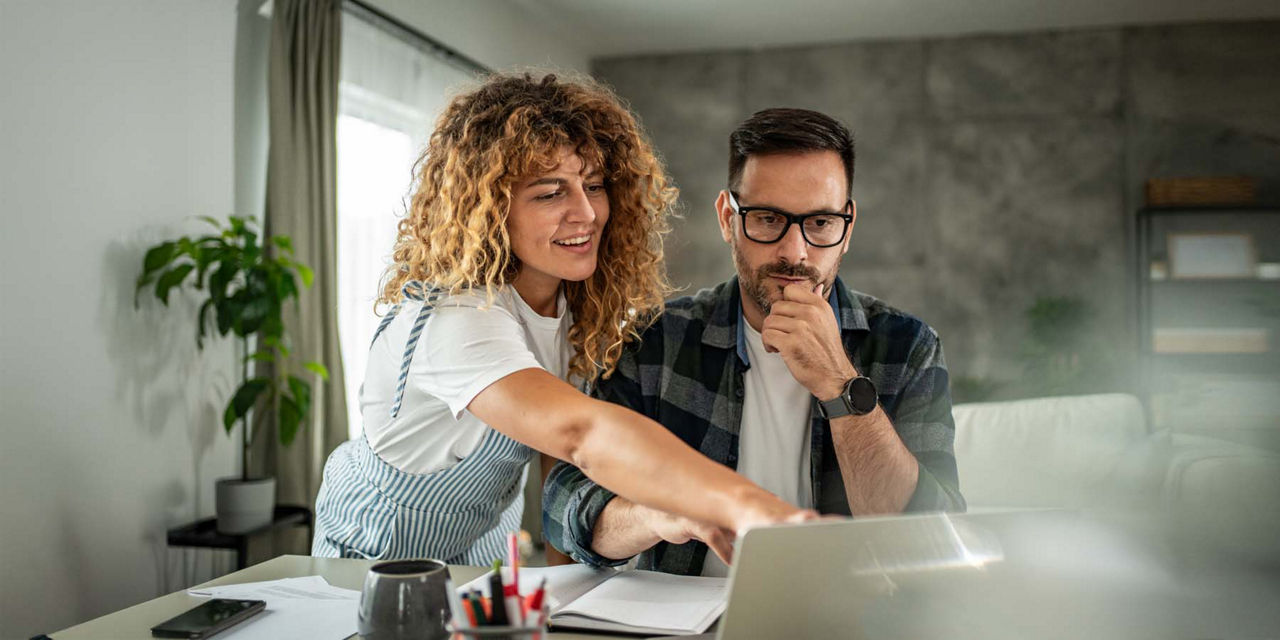 Junger Mann und junge Frau sitzen vor ihrem Laptop