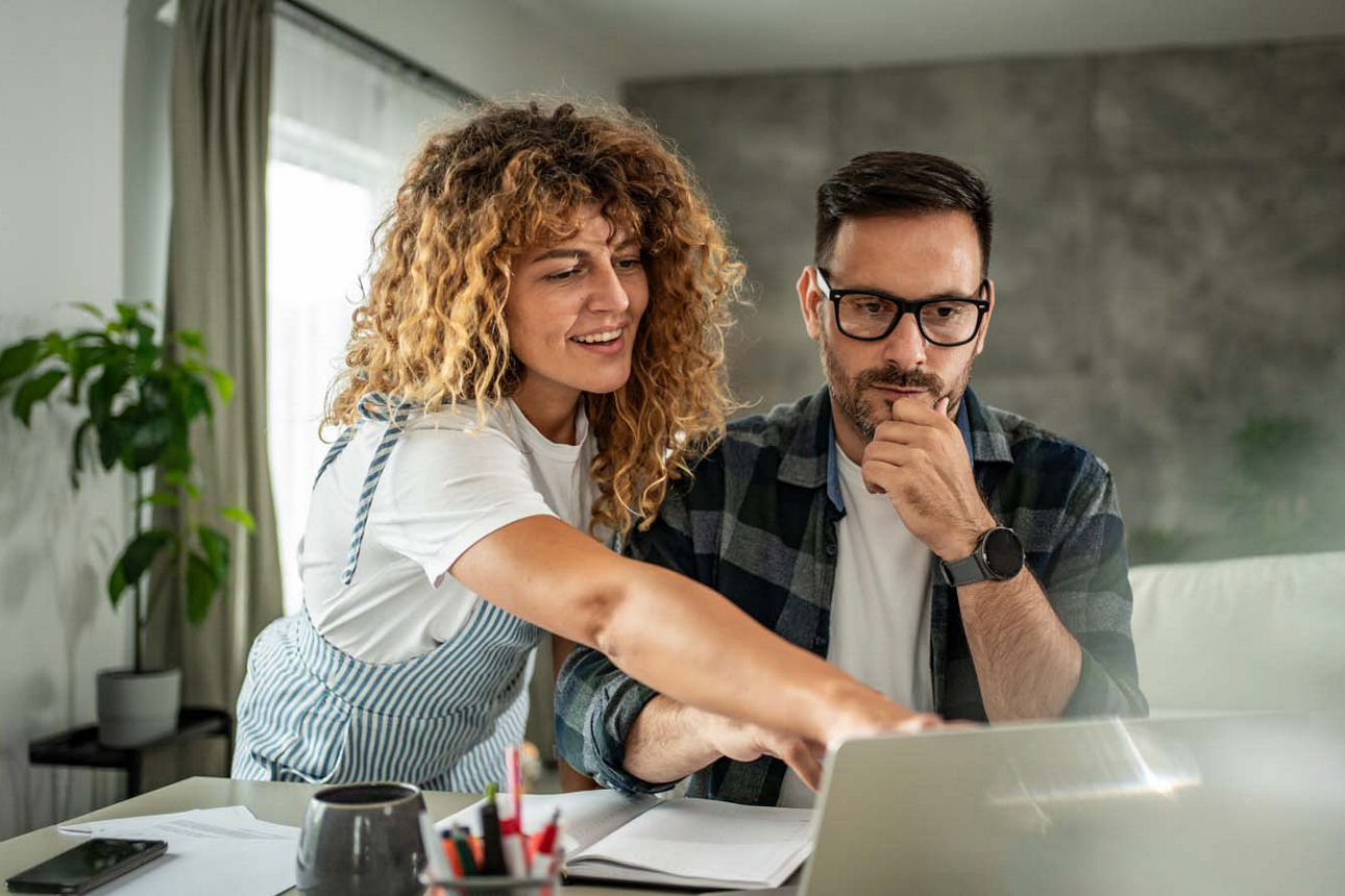 Junger Mann und junge Frau sitzen vor ihrem Laptop