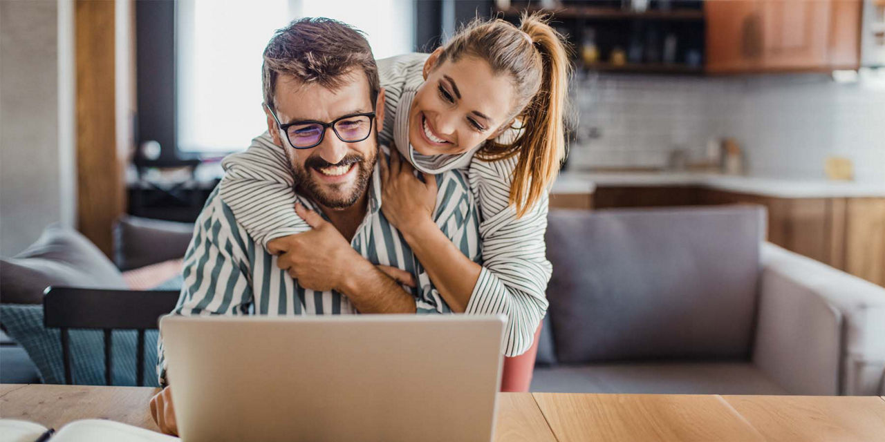 Mann und Frau schauen zufrieden lächelnd auf den Laptop