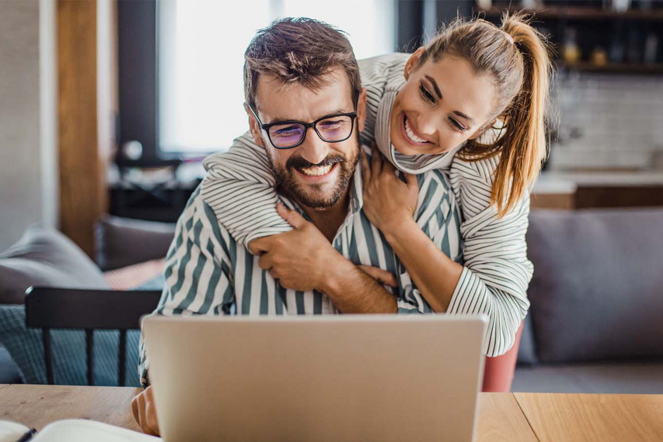Mann und Frau schauen zufrieden lächelnd auf den Laptop
