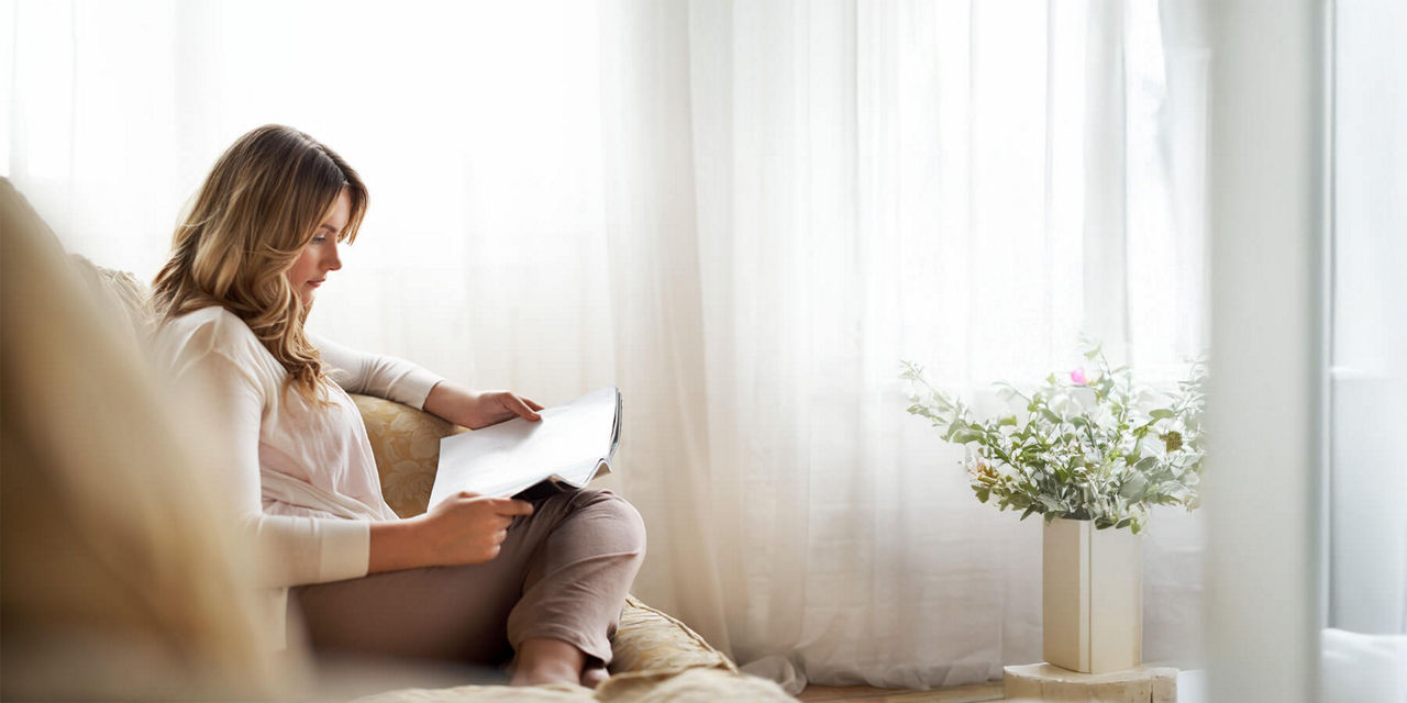 Frau liest das Kundenmagazin Nordlicht auf dem Sofa
