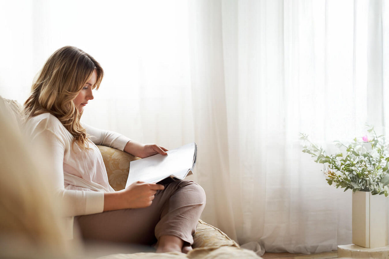 Frau liest das Kundenmagazin Nordlicht auf dem Sofa