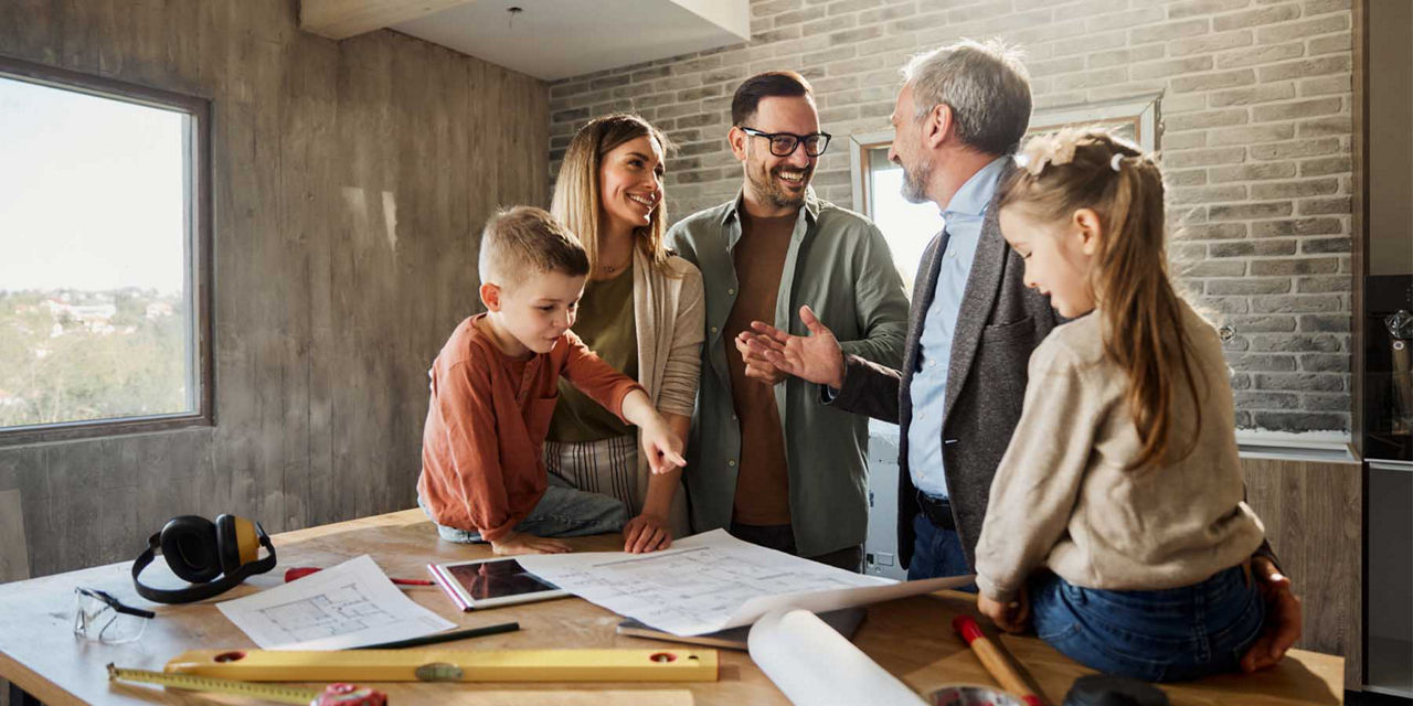 Eine junge Familie spricht glücklich mit dem Architekten über die Hausbaupläne