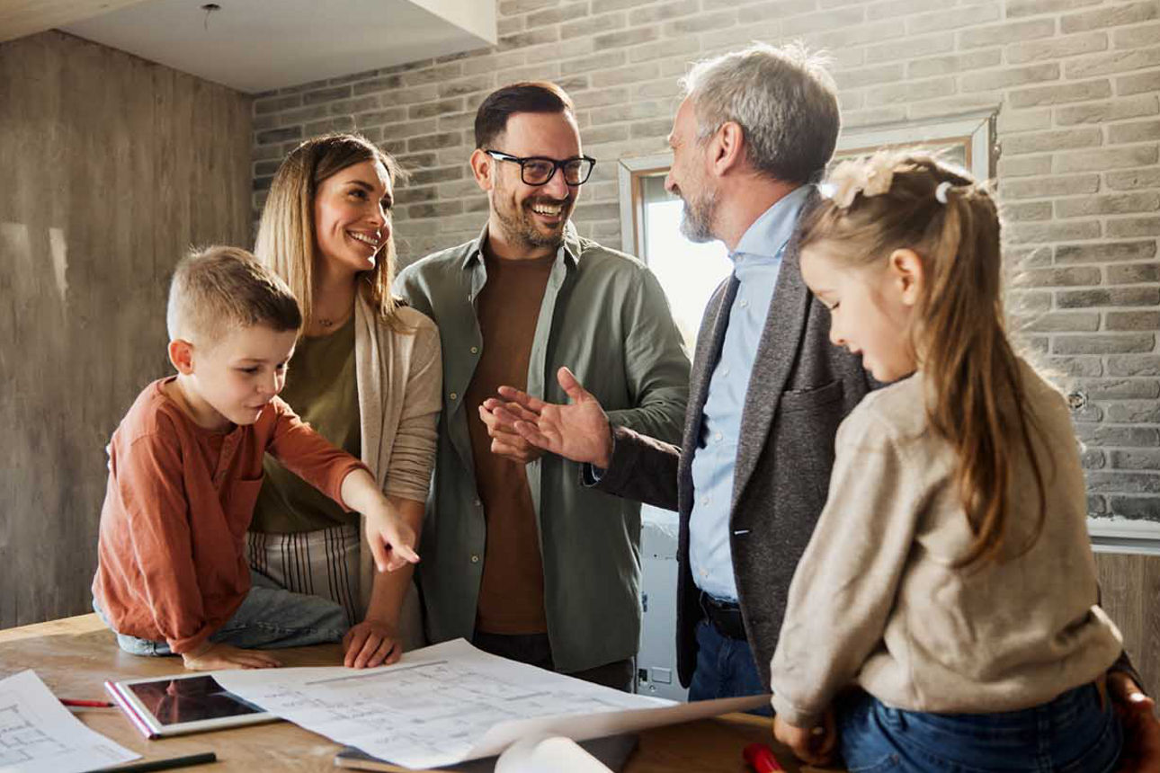 Eine junge Familie spricht glücklich mit dem Architekten über die Hausbaupläne