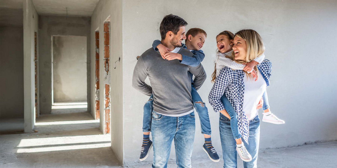 Eine junge Familie spielt im Rohbau ihres Eigenheims