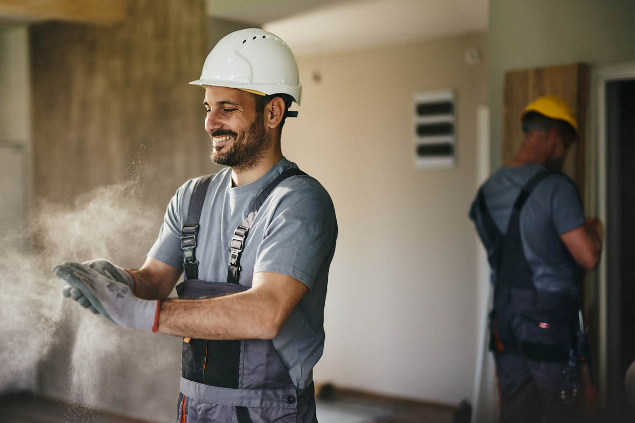 Ein junger Mann scheint überglücklich während er am Haus arbeitet