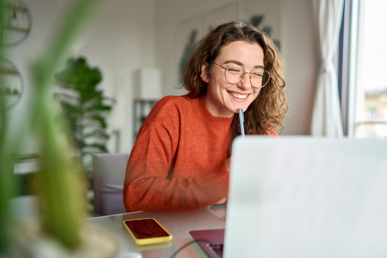 Frau sitzt am Laptop und lächelt