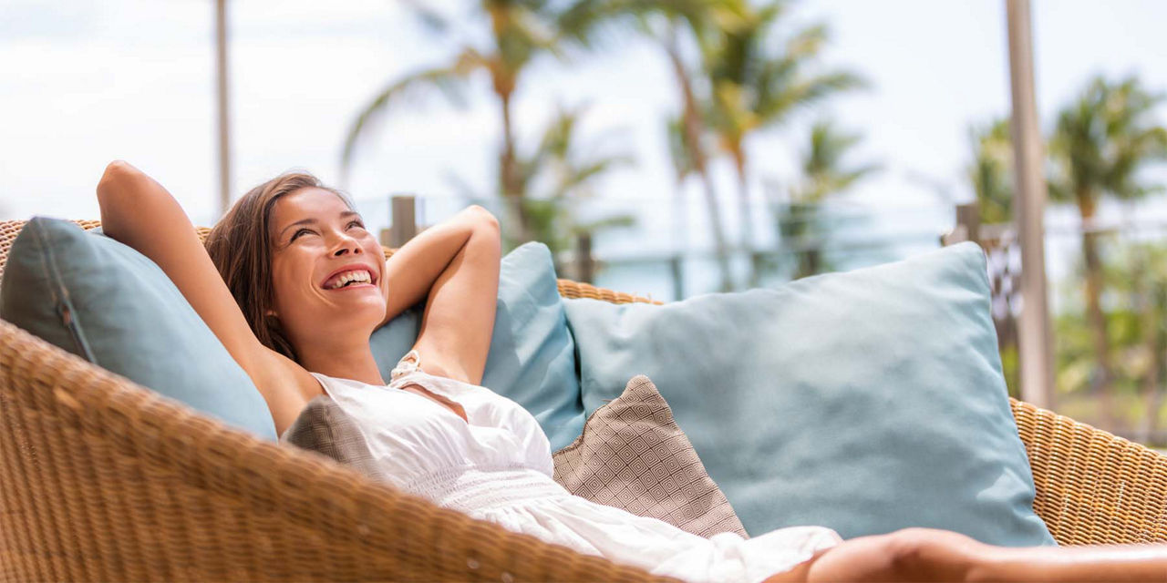 Junge  Frau sitzt am Strand und freut sich 