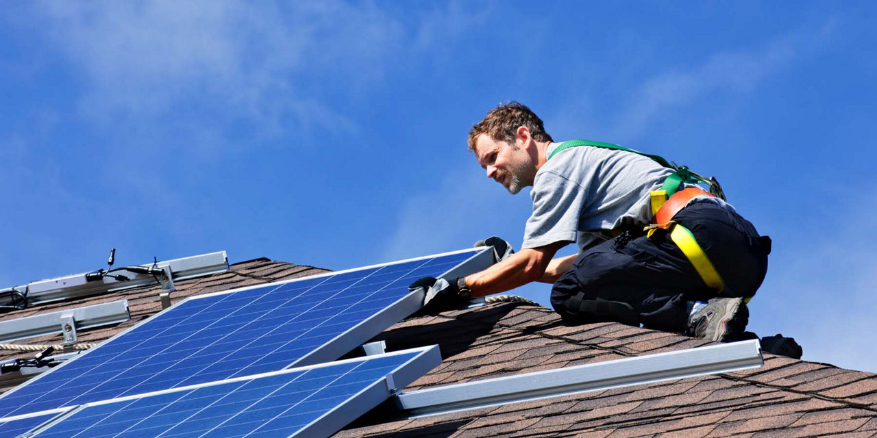 Monteur in Arbeitskleidung verbaut eine Solaranlage auf dem Dach 