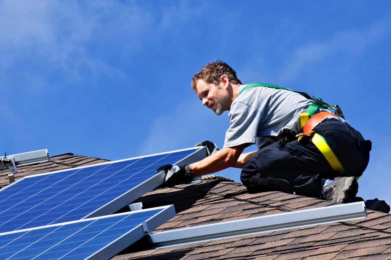 Monteur in Arbeitskleidung verbaut eine Solaranlage auf dem Dach 