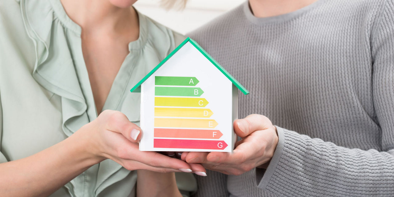 Ehepaar hält ein Modellhaus in der Hand, welches auf die Energieklassen hinweist