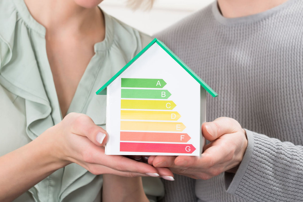 Ehepaar hält ein Modellhaus in der Hand, welches auf die Energieklassen hinweist