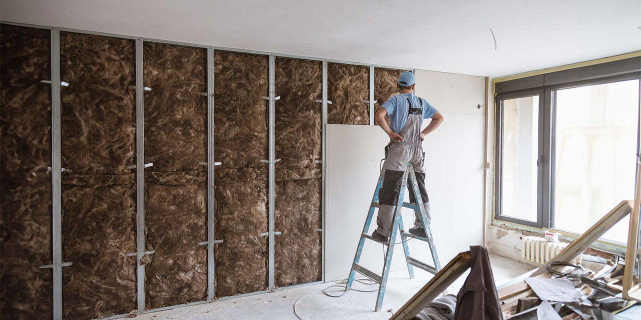 Handwerker baut eine Trockenbauwand inklusive Wärmedammung auf
