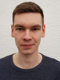 Ein Bild eines Stipendiaten. Er trägt ein blaues Tshirt und ist brünett.