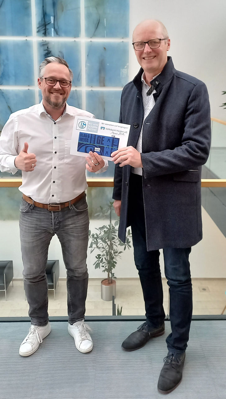 Zwei Männer, die ein Schild mit den Namen „BLAU & EGER WEISS“ halten.